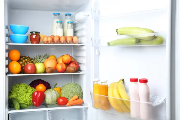 Open fridge full of vegetables and fruits