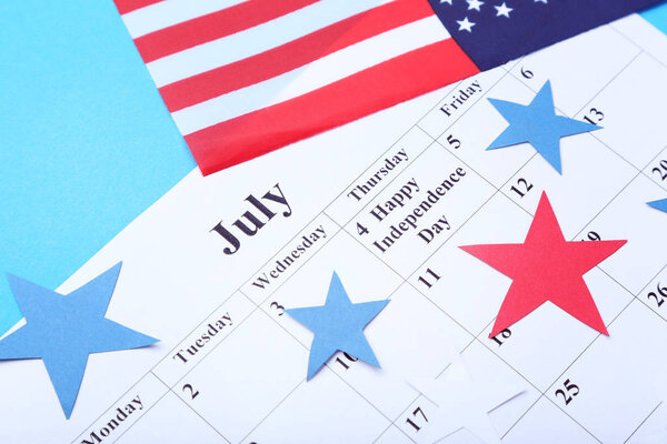 American flag and paper July calendar on blue background