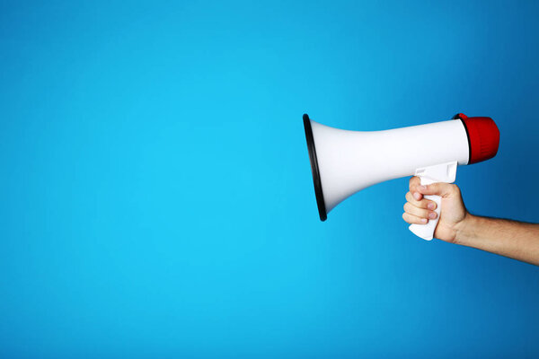 Female hand holding megaphone on blue background