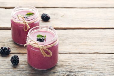 Böğürtlen yoğurt şişelerde gri ahşap tablo