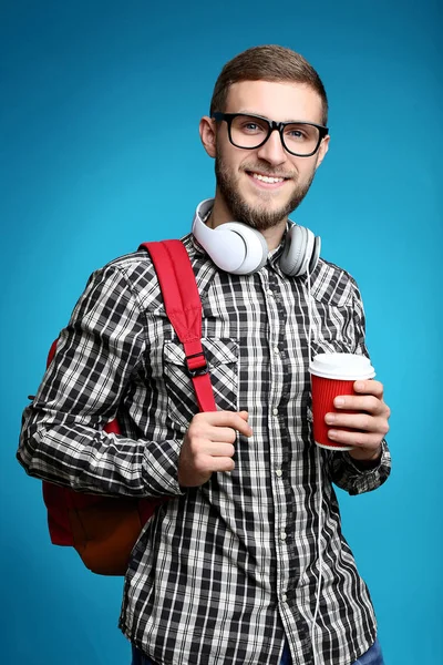 年轻人与背包 耳机和杯子咖啡在蓝色背景 — 图库照片