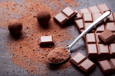 Ahşap masa kaşık kakao tozu ile çikolata parçaları