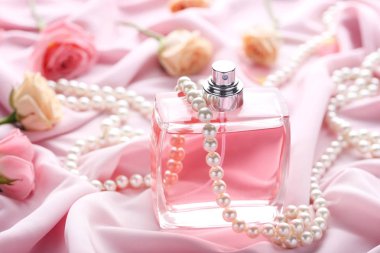 Gül ve saten arka plan üstündeki parfüm şişesi