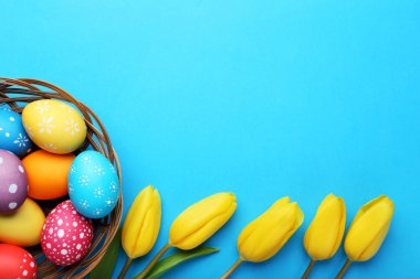 Sarı laleler üzerinde mavi arka plan ile sepet içinde renkli Paskalya yumurtaları