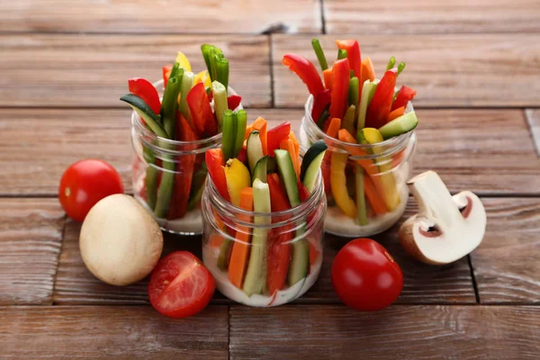 Kahverengi ahşap masa üzerinde bardaklarda sebze dilimlenmiş