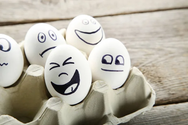 Αυγά Αστεία Πρόσωπα Χάρτινη Συσκευασία Ξύλινο Τραπέζι — Φωτογραφία Αρχείου