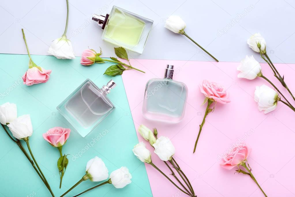 Perfume bottles with flowers on colorful background