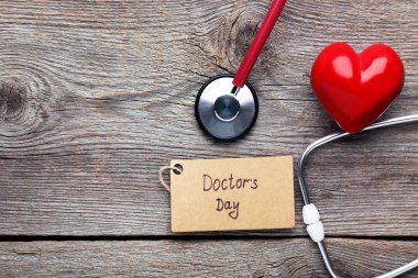 Yazıt doktorlar gün stetoskop ve kırmızı kalpli ahşap masa