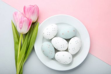 Paskalya yumurtaları renkli arka plan üzerinde plaka ile pembe laleler