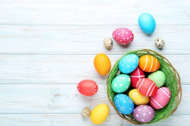 Ahşap masa üzerinde sepetteki renkli Paskalya yumurtaları