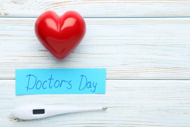Yazıt doktorlar gün termometre ve kırmızı kalpli ahşap masa