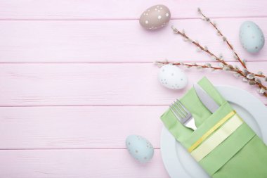 Paskalya yumurtaları ve pembe ahşap masa üzerinde ağaç dalları ile mutfak bıçakları
