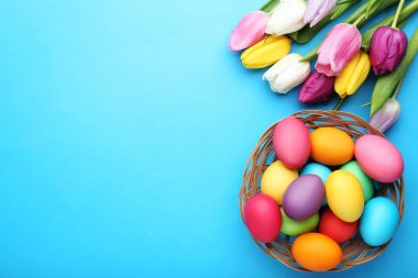 Lale mavi arka plan ile sepet içinde renkli Paskalya yumurtaları