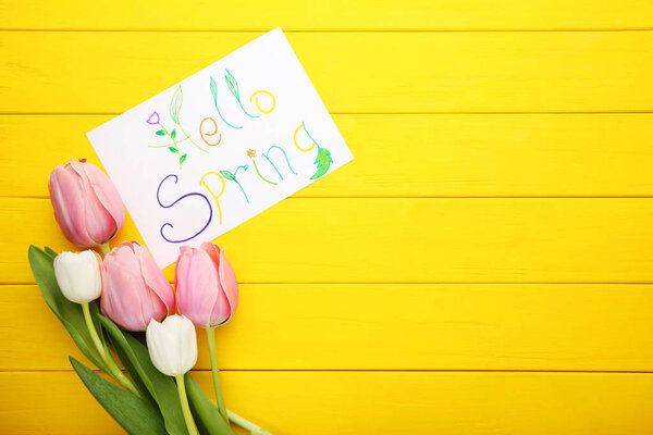Inscription Hello Spring with tulips on yellow wooden table