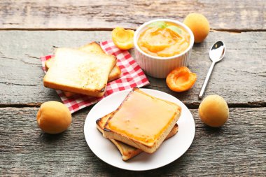 Ekmek tost gri ahşap masa üzerinde kase kayısı reçeli