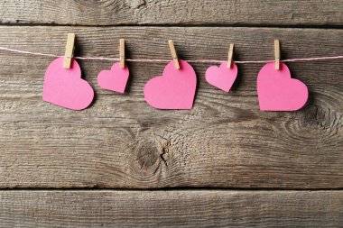 Pembe kağıt kalpleri üzerinde ahşap arka plan asılı