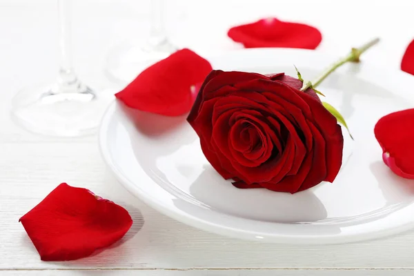 木製のテーブルに白い皿に赤いバラ — ストック写真