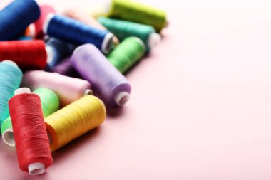 Pembe bir arka plan üzerinde renkli iplik makaralar