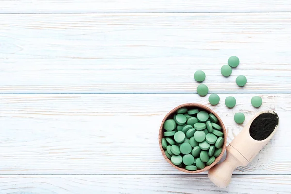 Spirulina powder and tablets on wooden table