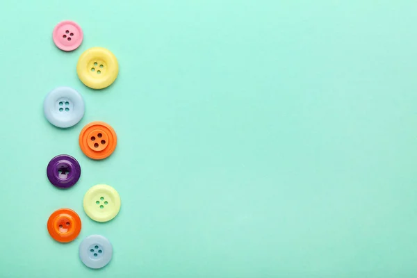Colorful sewing buttons on mint background
