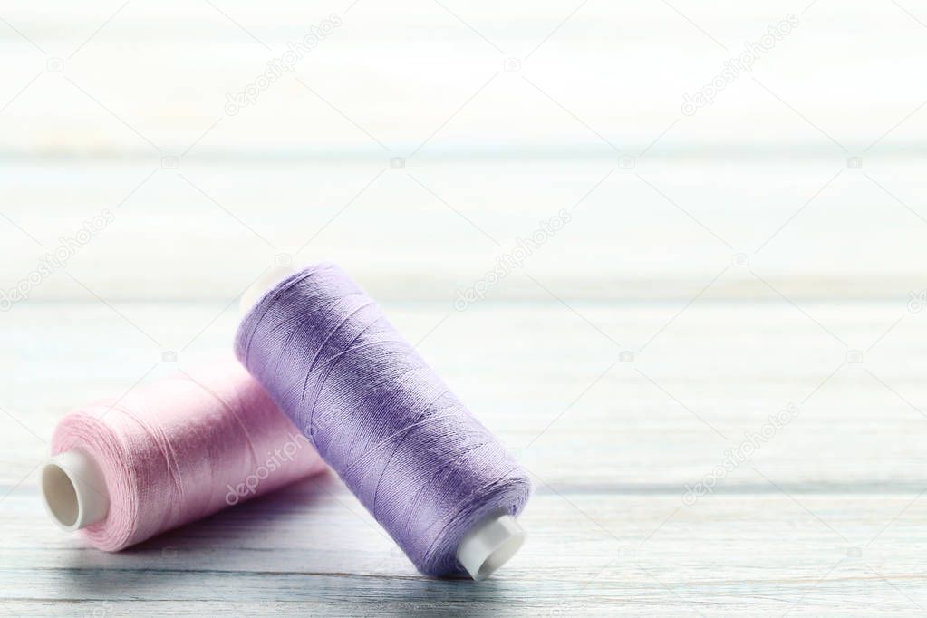 Colourful thread spools on white wooden table