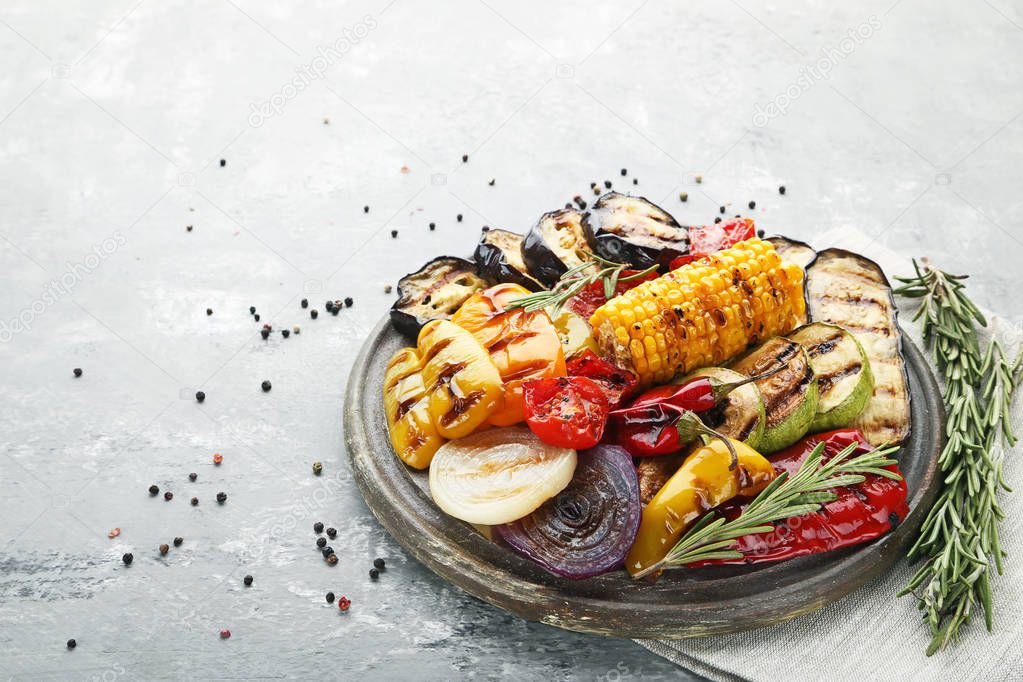 Grilled vegetables on brown cutting board with rosemary