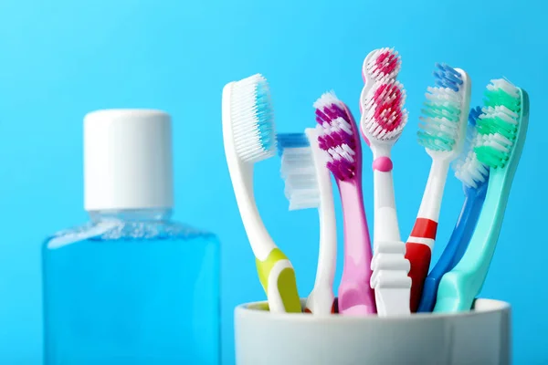 Close Van Kleurrijke Tandenborstels Beker Met Mondwater Fles Blauwe Achtergrond — Stockfoto
