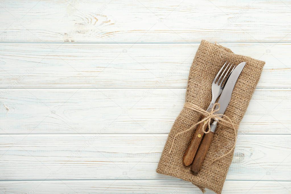 Fork and knife with sackcloth on wooden table