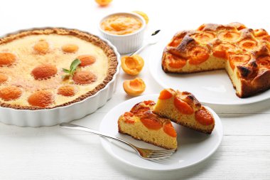 Beyaz ahşap masa üzerinde meyve ile kayısı pasta grafiğin dilimlerini