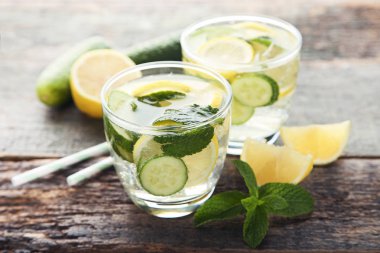 Ahşap masa üzerinde bardaklarda limonata salatalık, limon ve nane yaprakları