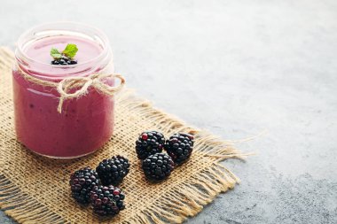 Böğürtlen yoğurt şişelerde gri ahşap tablo