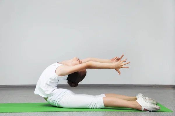 Young girl doing exercises on green yoga mat