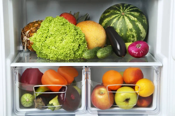 Open fridge full of vegetables and fruits