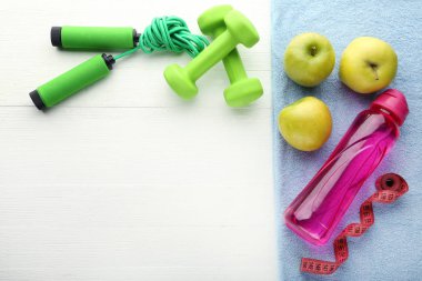 Pembe şişe, yeşil elma, halter ve beyaz tablo atlama ipi