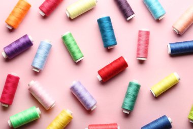 Pembe bir arka plan üzerinde renkli iplik makaralar