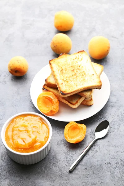 Ekmek tost gri ahşap masa üzerinde kase kayısı reçeli
