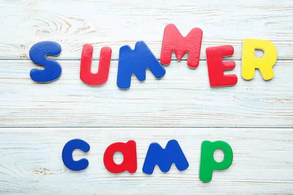 Inscription Summer Camp by colored letters on wooden table