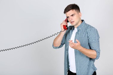 Young man with handset on grey background