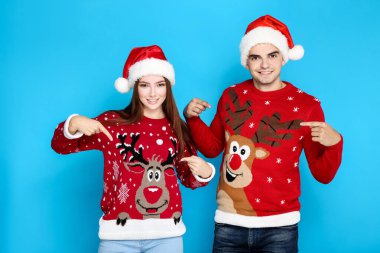 Noel süveteri ve Noel Baba şapkası giyen güzel bir adam ve kadın.
