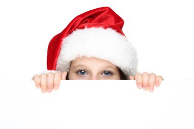 Beyaz arka planda boş tahtası olan Noel süveteri ve şapkalı küçük bir kız.