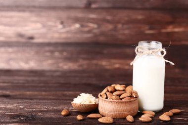 Kahverengi ahşap masa üzerinde şişe badem ve süt