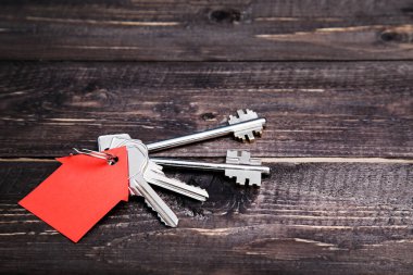 Kahverengi ahşap masa üzerinde ev sembolü ile gümüş anahtar
