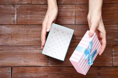 Kahverengi ahşap masa üzerinde kadın elleri açılış hediye kutusu