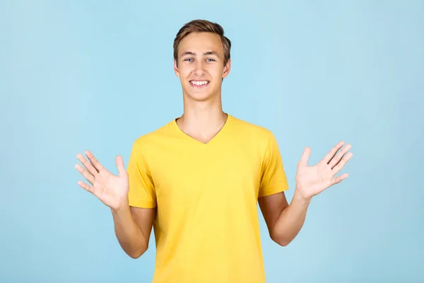 Porträtt av ung man i gul t-shirt på blå bakgrund — Stockfoto