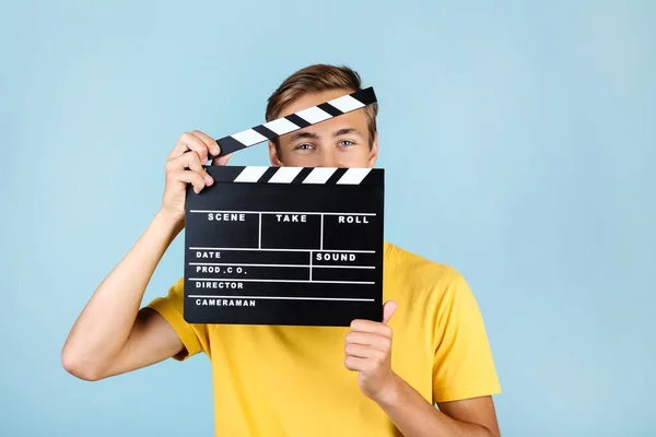 Ung man med Clapper Board på blå bakgrund — Stockfoto