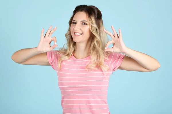 Jonge vrouw tonen OK op blauwe achtergrond — Stockfoto