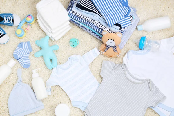 Ropa de bebé con juguetes y pañales en la alfombra —  Fotos de Stock