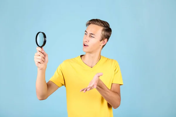 Jonge man met vergrootglas op blauwe achtergrond — Stockfoto