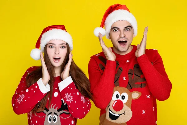 Hermoso hombre y mujer en suéteres de Navidad y sombreros de santa en — Foto de Stock