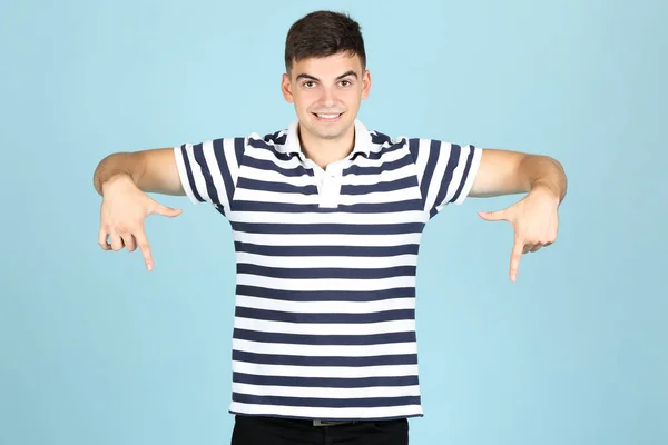 Junger Mann zeigt Finger nach unten auf blauem Hintergrund — Stockfoto